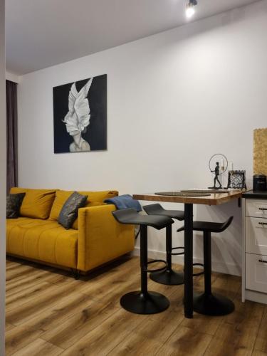 salon z żółtą kanapą i stołem w obiekcie Apartament Wyspiański w mieście Sanok