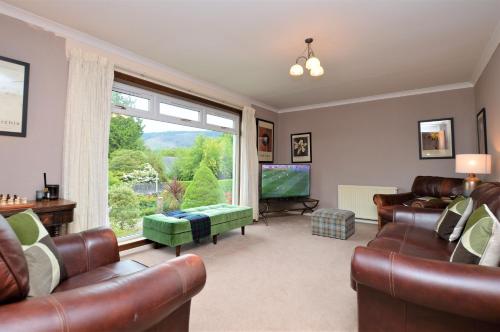a living room with leather furniture and a large window at Brookfield in Sandbank