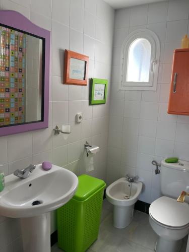 een badkamer met een wastafel, een toilet en een spiegel bij Pueblo Marinero in Novo Sancti Petri