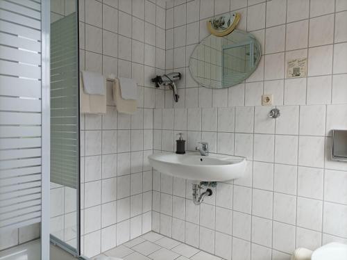 a white tiled bathroom with a sink and a mirror at Pension Landgasthof Darzer Eck in Altenhof
