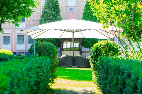 an umbrella in the middle of a yard with bushes at Hotel Globo in Formigine