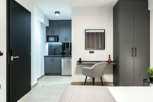 a kitchen with black cabinets and a white chair at Nerea Boutique Suites Karystos in Karistos