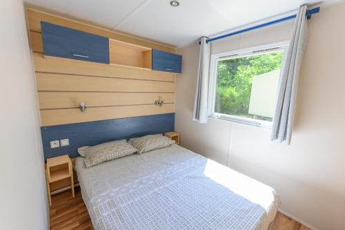 une petite chambre avec un lit et une fenêtre dans l'établissement Mobil-home le ROBINSON, à Mirgaudon