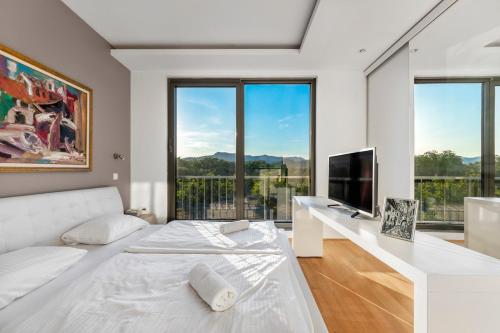 biała sypialnia z białym łóżkiem i telewizorem w obiekcie Contemporary apartment with rooftop terrace in Maribor w Mariborze