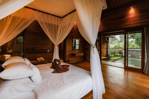 um quarto com 2 camas com lençóis brancos e cortinas em Villa Emerald: Precious Find in the Central Ubud em Ubud