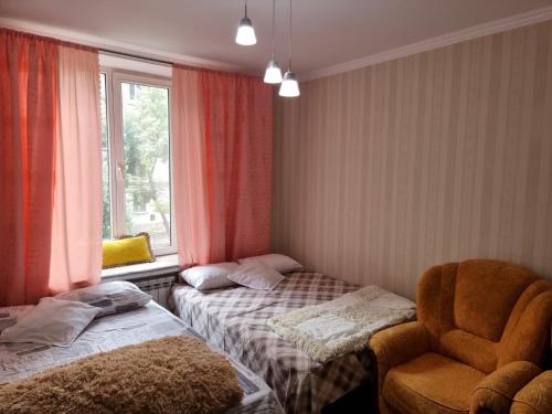 a room with two beds and a chair and a window at Comfortable apartment for you in Chişinău