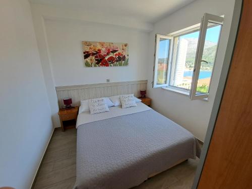 a white bedroom with a bed and a window at Apartments Šišević - Comfort Apartments with Balconies and Sea View in Slano