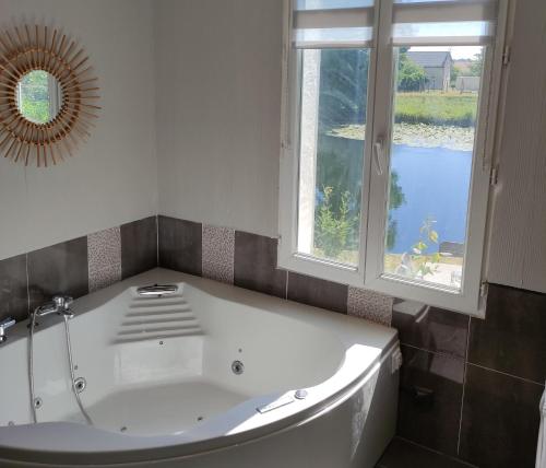 uma banheira branca na casa de banho com uma janela em Détente au bord du Loir - Gîte 2 em Les Roches-lʼÉvêque
