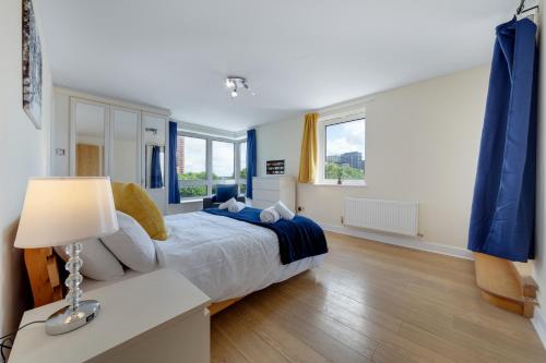 een slaapkamer met een bed en een lamp op een bureau bij Flourish Apartment - Constant Court - Canary Wharf in Londen