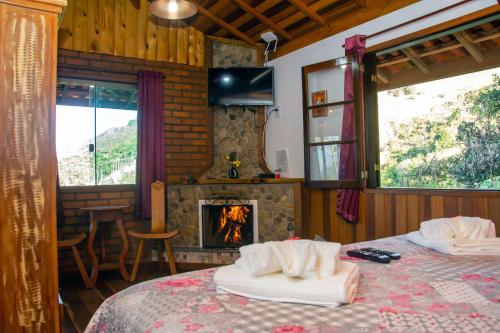 um quarto com lareira e uma cama com toalhas em Chales Encanto do sol em Visconde de Mauá