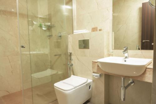 a bathroom with a toilet and a sink and a shower at THE RUNWAY HOTEL in Cochin