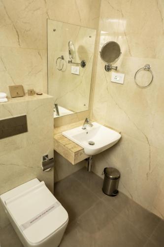 a bathroom with a toilet and a sink and a mirror at THE RUNWAY HOTEL in Cochin