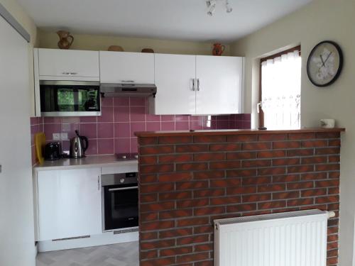 a kitchen with white cabinets and a brick wall at Gîte "Le Rucher" in Romanswiller