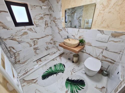 a bathroom with marble walls and a toilet and a mirror at Bella Vista Bungalow in Turda