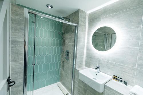 a bathroom with a shower and a sink and a mirror at The Forge in Swansea