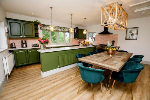 a kitchen with green cabinets and a wooden table and chairs at The Forge in Swansea