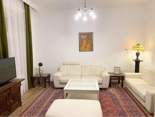 sala de estar con sofás blancos y TV de pantalla plana en Platános Apartman Tata, en Tata