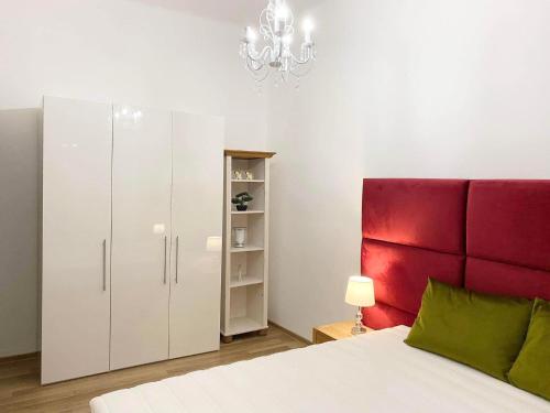a bedroom with a white bed and a red headboard at Platános Apartman Tata in Tata
