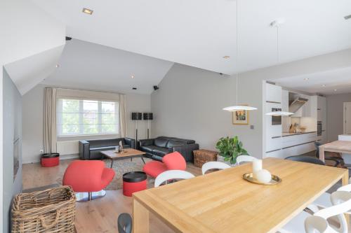 a living room with a table and red chairs at Ruime woning met grote omheinde tuin in Hasselt