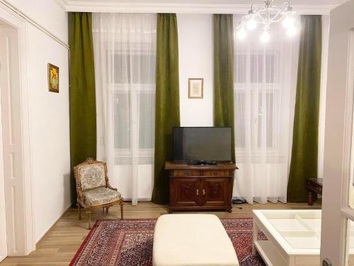 a living room with a tv and a chair at Platános Apartman Tata in Tata