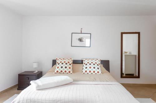 a bedroom with a large white bed with pillows and a mirror at Appartamento Topo in Trarego