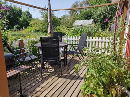 een houten terras met een tafel en stoelen in een tuin bij Lillstugan - Centralt och havsnära i lugnt villområde in Falkenberg