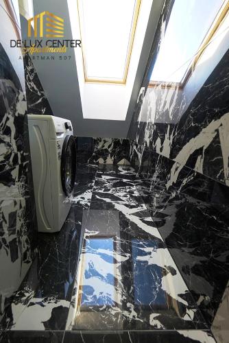 a bathroom with a black and white marble floor at DeLux Center Apartments Inđija in Inđija