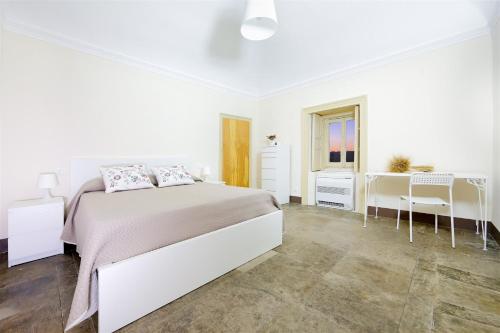 a white bedroom with a bed and a desk at Villa Polara in Modica
