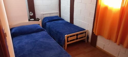two beds in a small room with blue sheets at Alojamiento Quincho Pascual in Las Compuertas