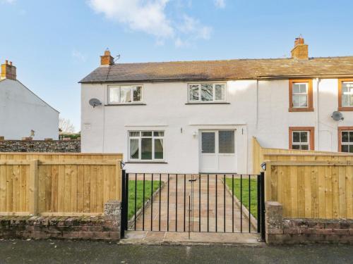 a white house with a gate and a fence at 1 Springfort Cottages in Penrith