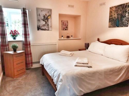 a bedroom with a large white bed and a window at Gwynedd House Flat 1 in Pentraeth