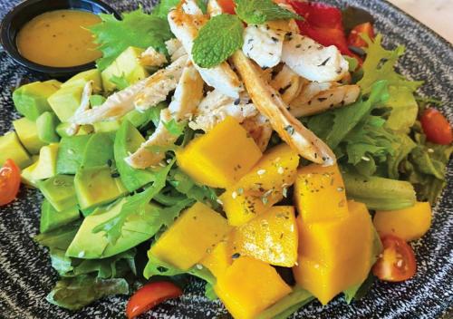 a salad with chicken and vegetables on a plate at Fraser Suites Diplomatic Area Bahrain in Manama