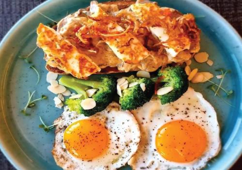 a blue plate with eggs and broccoli on a table at Fraser Suites Diplomatic Area Bahrain in Manama