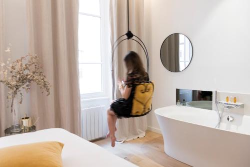 a young girl sitting in a bathroom looking out the window at MiHotel Charité in Lyon