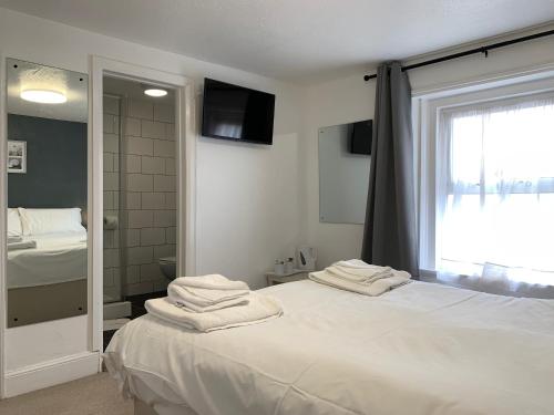 a bedroom with a large white bed with a mirror at The Royal Clarence Hotel (on the Seafront) in Burnham on Sea
