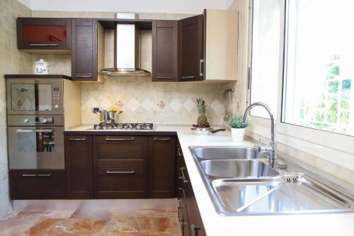 uma cozinha com armários castanhos, um lavatório e uma janela em Appartamento con terrazzo a Capodimonte by Wonderful Italy em Nápoles