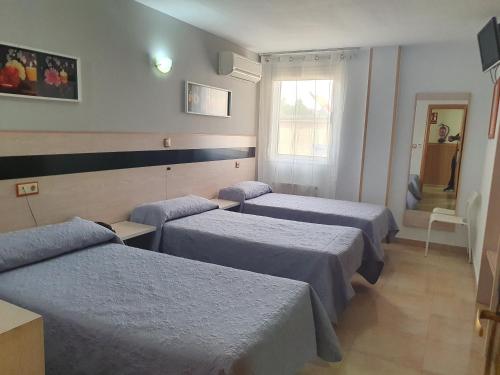a hotel room with three beds and a window at Hostal Fronton in Alcobendas