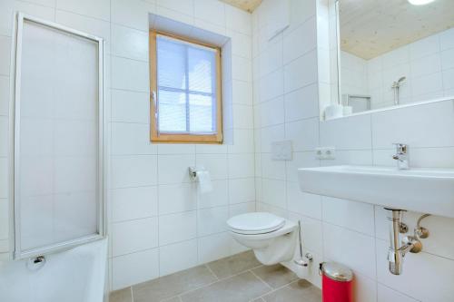 a white bathroom with a toilet and a sink at Grünerstein Chalet Jungbrunnen in Bramberg am Wildkogel