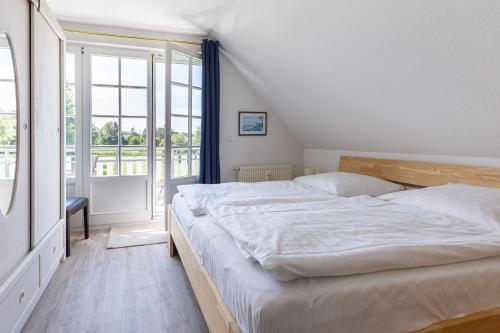 een slaapkamer met een groot bed en een groot raam bij Wiesenblick in Ahrenshoop