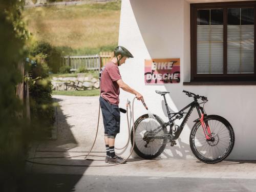 a man is washing a bike on the side of a building at alpina&more APARTMENTS I ZIMMER in Serfaus