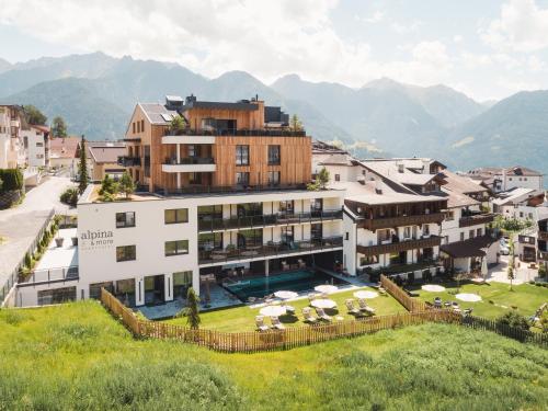 a hotel with a swimming pool and mountains in the background at alpina&more APARTMENTS I ZIMMER in Serfaus