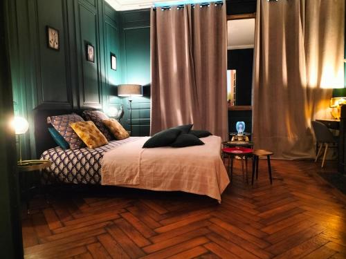 um quarto com paredes verdes e uma cama com almofadas em Nancy Vieille Ville Stanislas em Nancy