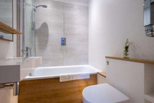 a bathroom with a tub and a toilet and a sink at Nutshell Cottage in Lymington