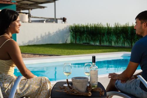 a man and a woman sitting at a table with wine glasses at Delmira Vineyard House in Águas de Moura