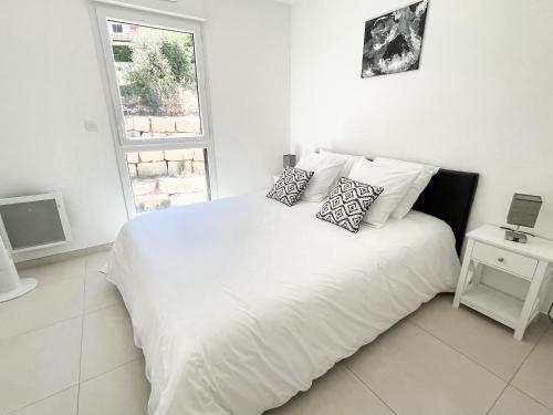 una camera da letto con un letto bianco con cuscini e una finestra di T2 NEUF TERRASSE PRES des PLAGES a Saint-Cyr-sur-Mer