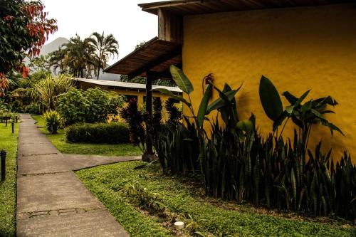 a sidewalk next to a yellow building with plants at Catarata Eco Lodge in Fortuna