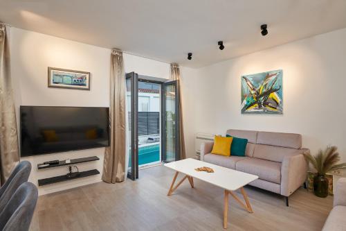 a living room with a couch and a tv at Villa Nika with private heated pool in Slano