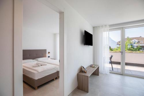 a white bedroom with a bed and a window at Apartments Curti - Himmelblau in Laives