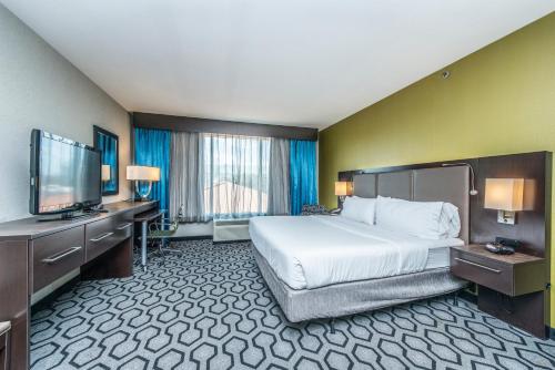 a hotel room with a bed and a flat screen tv at Holiday Inn Express & Suites Charleston Arpt-Conv Ctr Area by IHG in Charleston