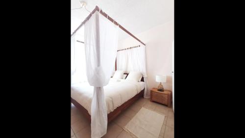a bedroom with a canopy bed with white curtains at Ness Home A Beautiful Village House in Maraussan